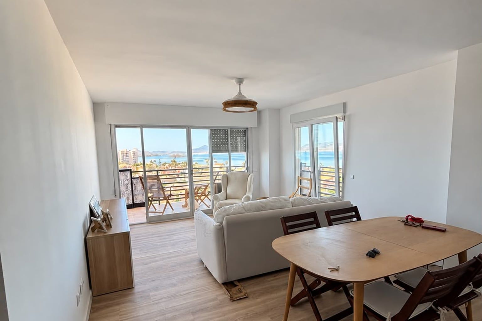 Salón reformado con suelo de madera y vistas al mar